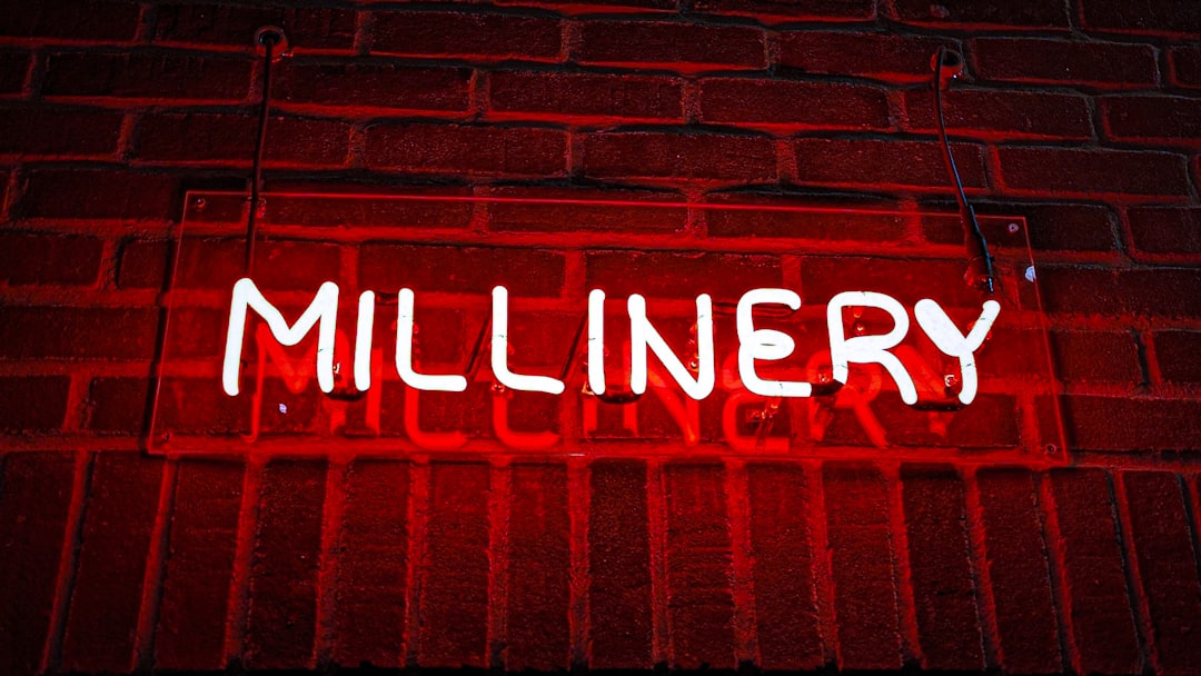 how to become a millionier - A red neon sign that reads millinery on a brick wall
