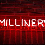 how to become a millionier - A red neon sign that reads millinery on a brick wall