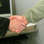 how to get a cra from dealership - two people shaking hands in front of a computer monitor